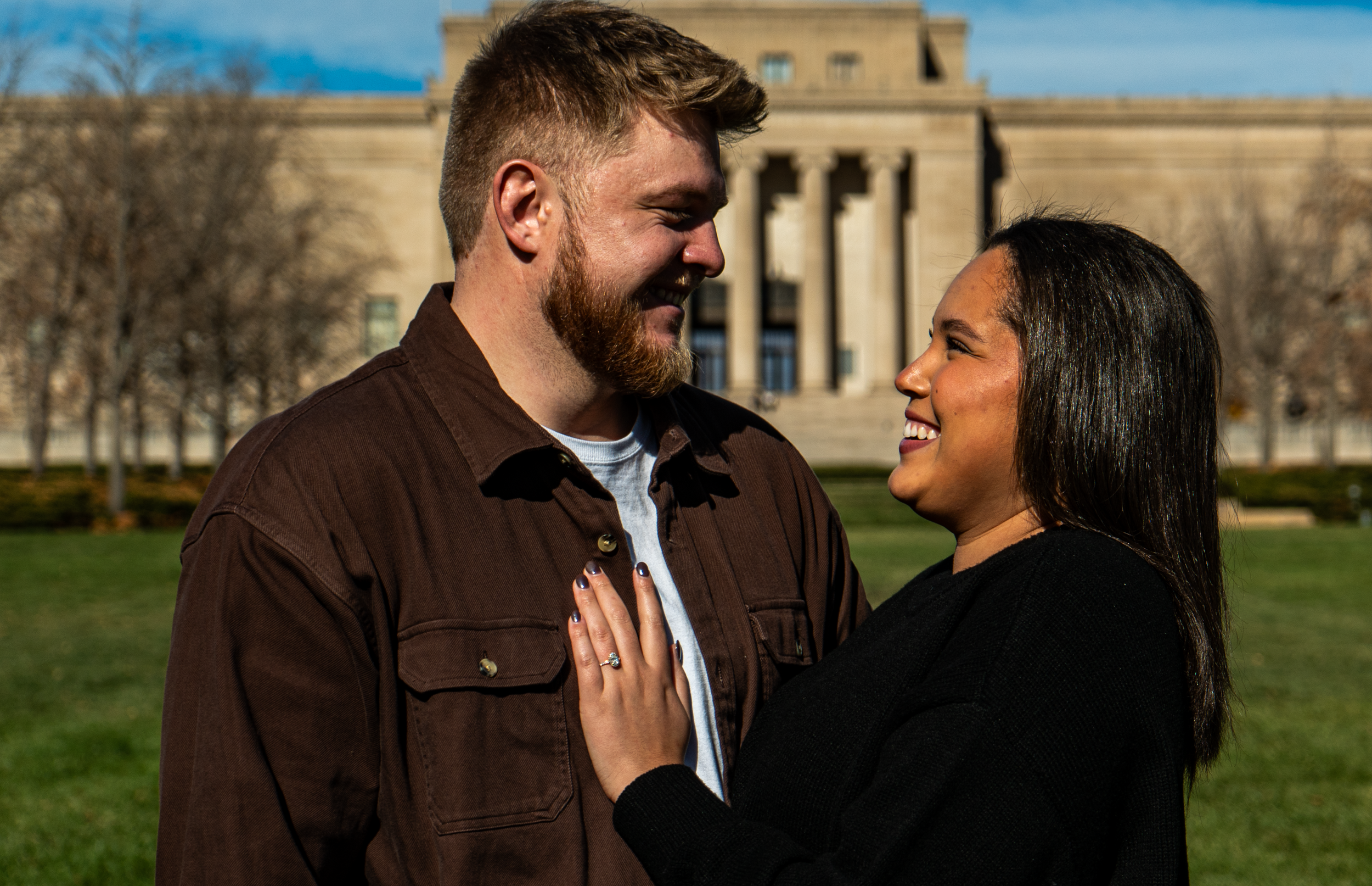 A smiling man and woman looking at each other outdoors, with the US Capitol building in the background.