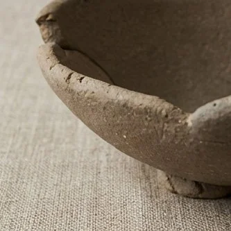 Close-up of unglazed yakishime stoneware bowl showing granular clay texture and folded rim