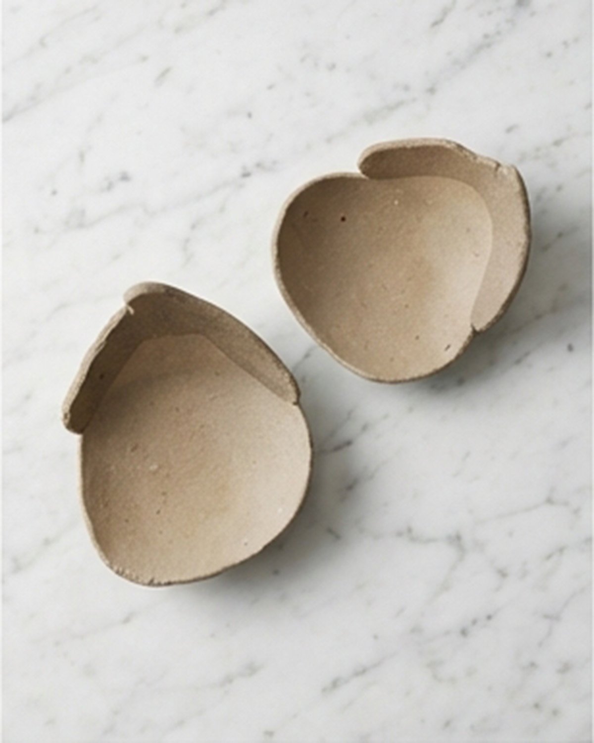 Yakishime unglazed stoneware bowl with folded petal-like rim viewed from above on marble surface