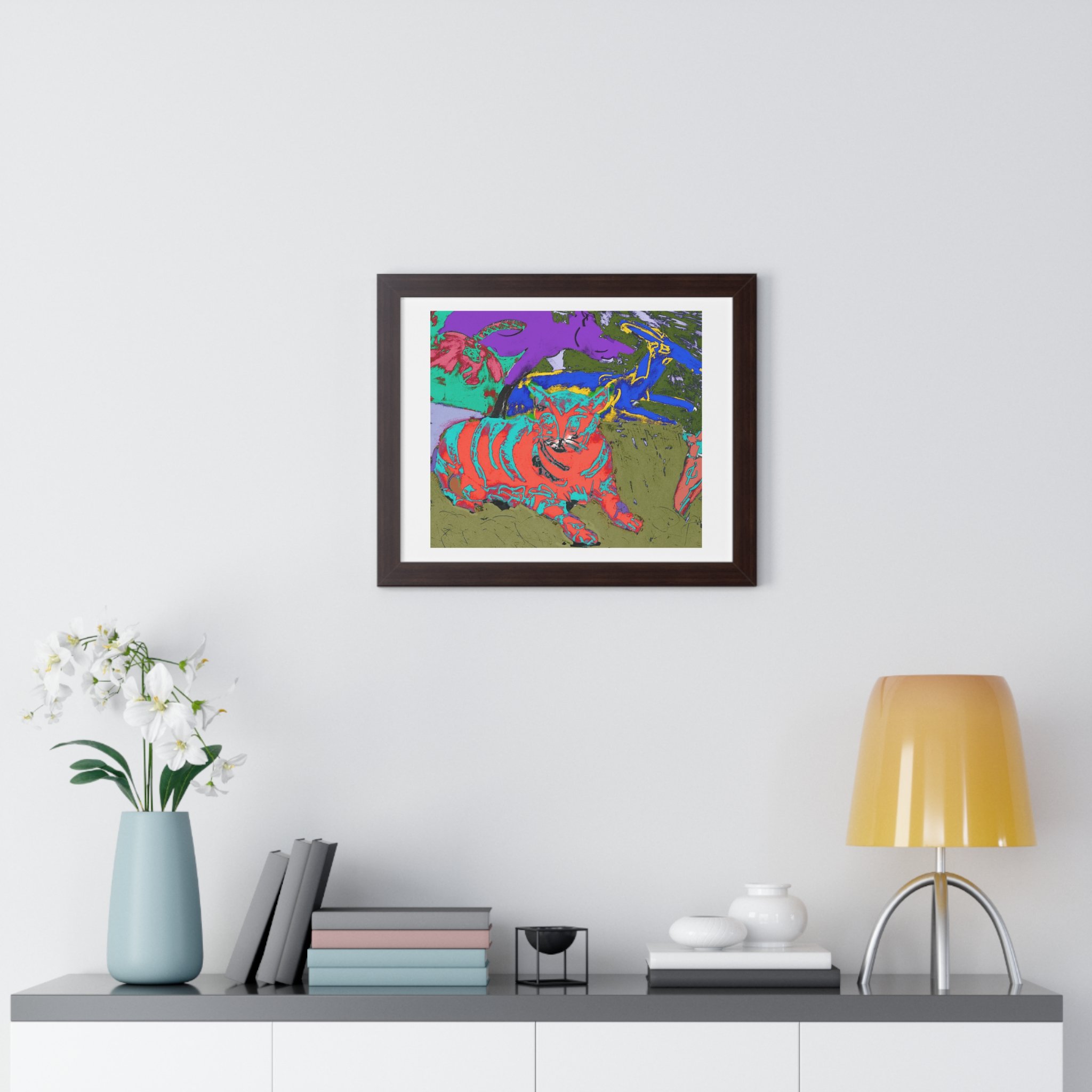 Colorful cat art print framed in walnut (dark brown) with a matte.  hang above a table with light blue vase and white flower, books, and lamp.