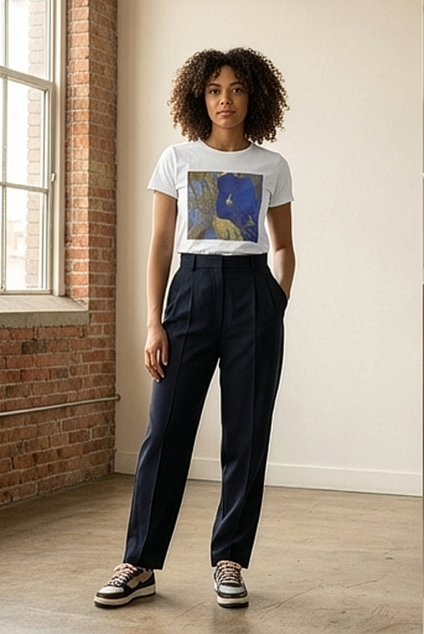 Female model standing by the window in a loft space wearing botanical (hibiscus flower) inspired white t-shirt