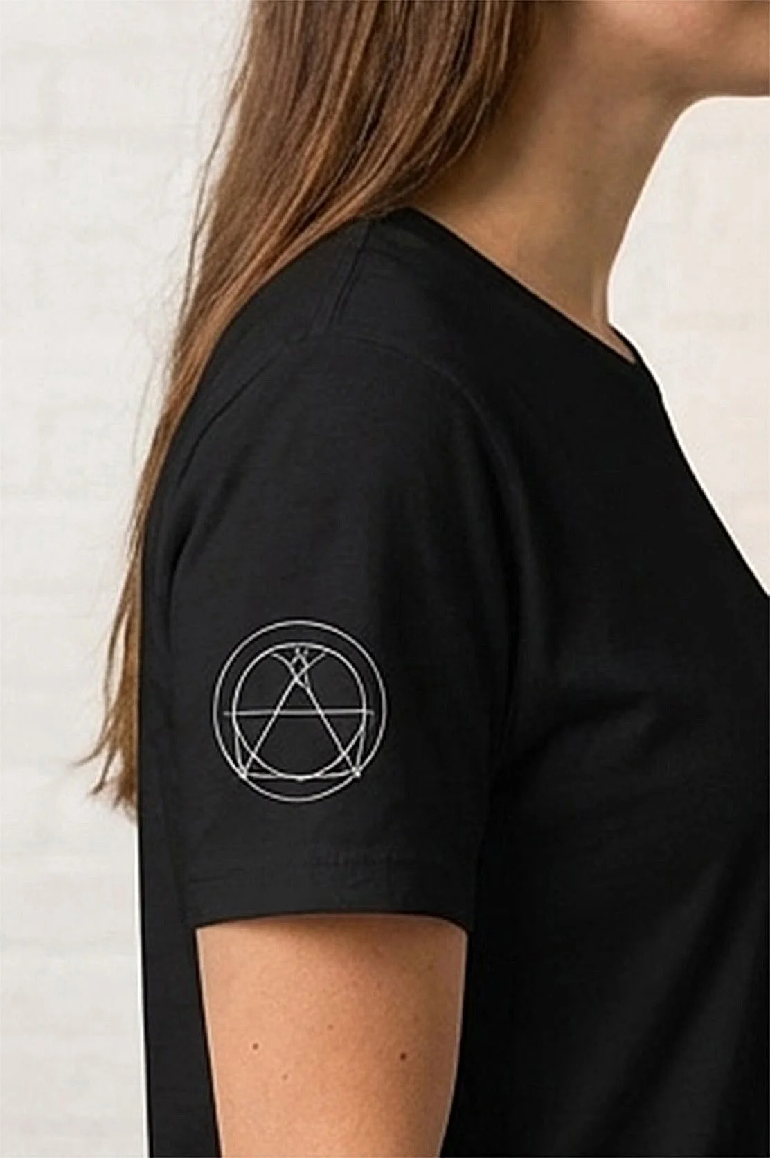 Focused view of side sleeve of  black crew neck t-shirt  with minimal white circle geometric design. The graphic appears to be a mechanical engineering symbol design.