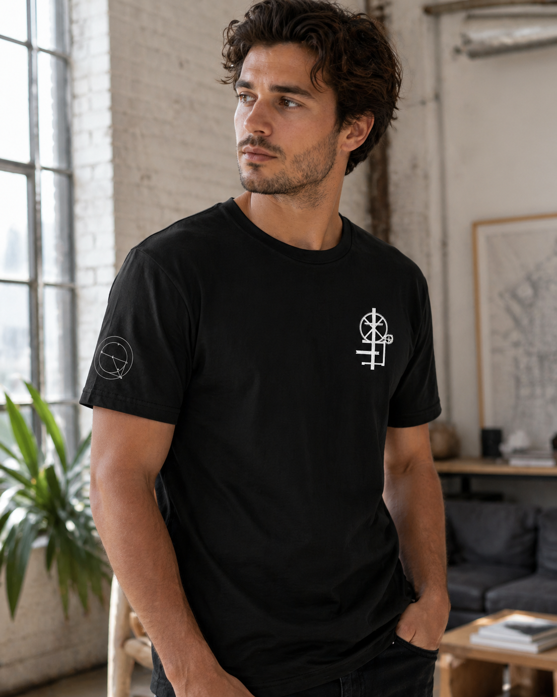 Male model wearing black crew neck t-shirt  with minimal white graphic on the chest. The graphic appears to be a mechanical engineering symbol design.