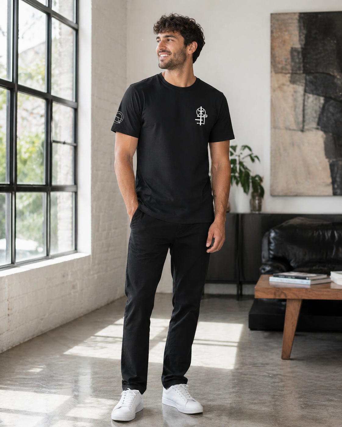 Male model wearing black crew neck t-shirt  with minimal white graphic on the chest. The graphic appears to be a mechanical engineering symbol design.