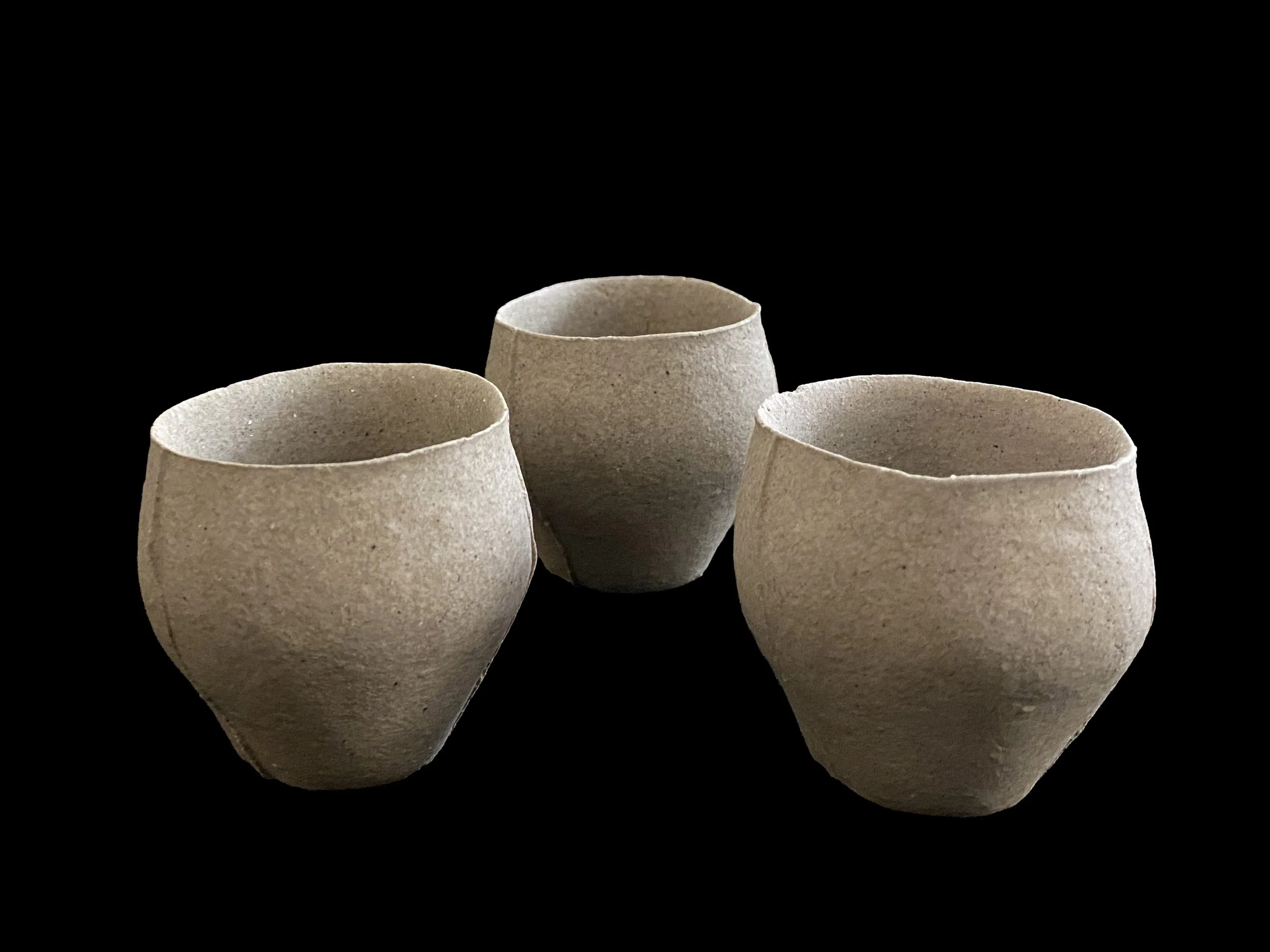 Handmade yakishime unglazed stoneware cup isolated on a black background showing natural clay texture