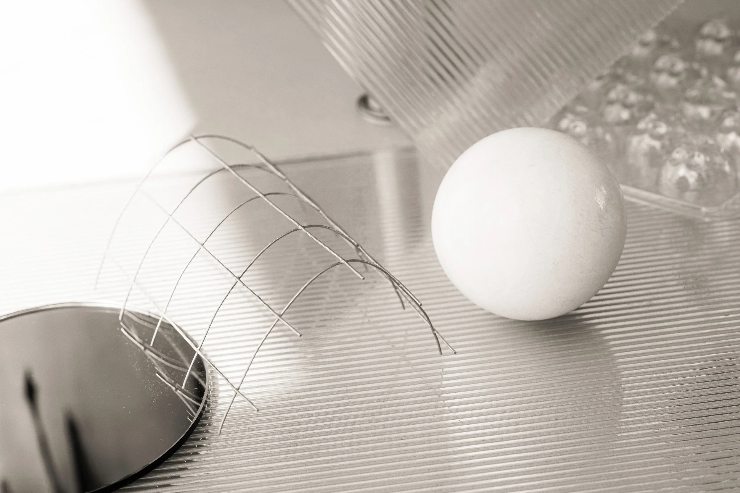 metallic objects with a soft white ball contrasting the hard against the soft yin young atmosphere.   The overall image creates a cool conceptual assemblage.