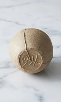 Single yakishime unglazed stoneware cup with organic texture resting on a marble surface in soft natural light