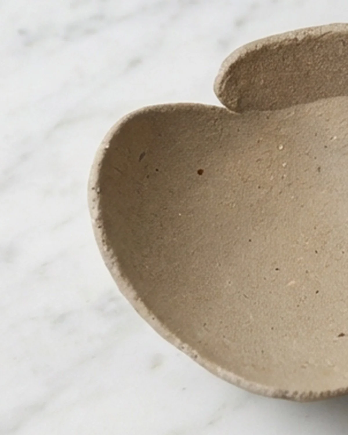 Close-up of unglazed yakishime stoneware bowl showing granular clay texture and folded rim