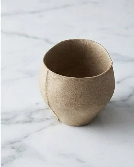 Single yakishime unglazed stoneware cup with organic texture resting on a marble surface in soft natural light