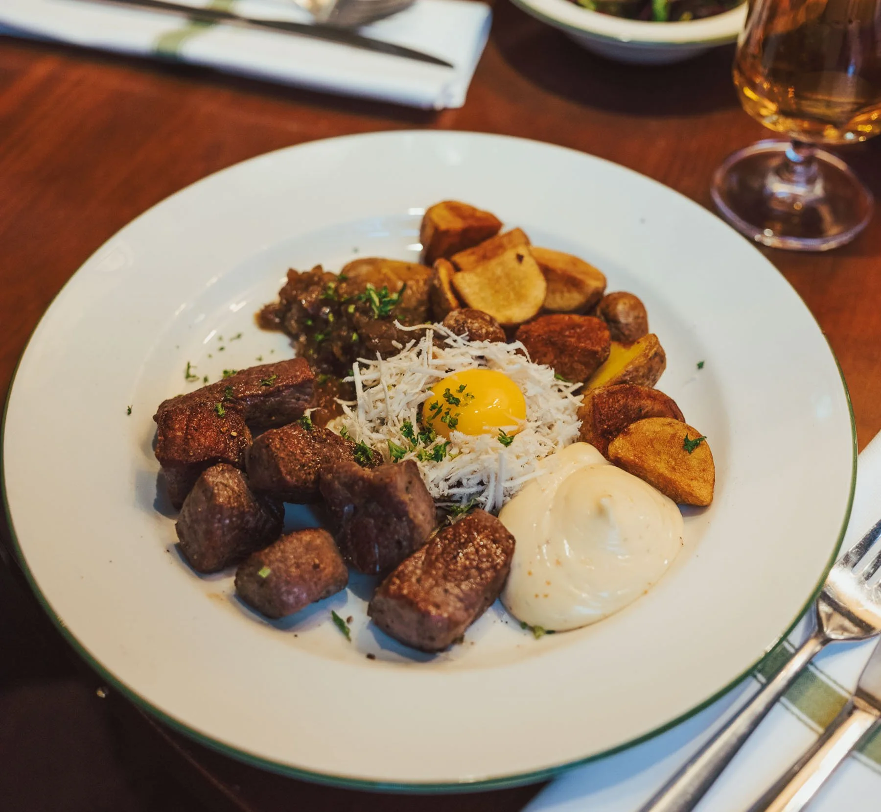 En tallrik med köttbullar, pommes frites, ett stekt ägg och en köttbit serveras på ett fat.
