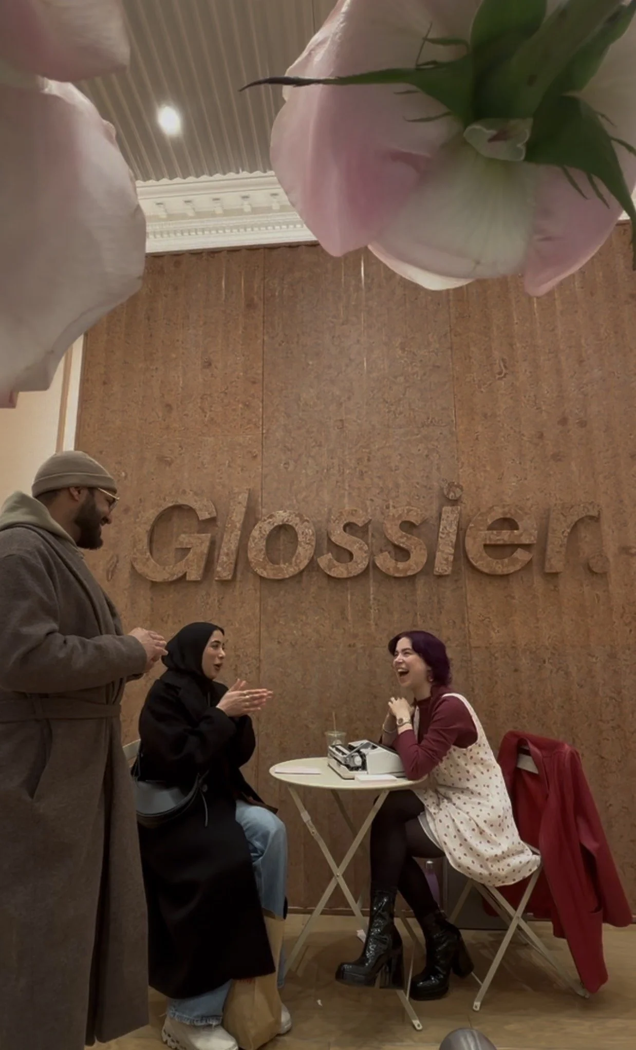 three people talking beside a typewriter on a table