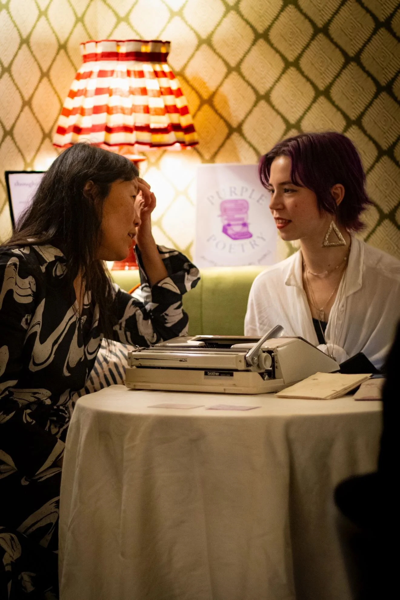 two people talking in front of a typewriter on a table