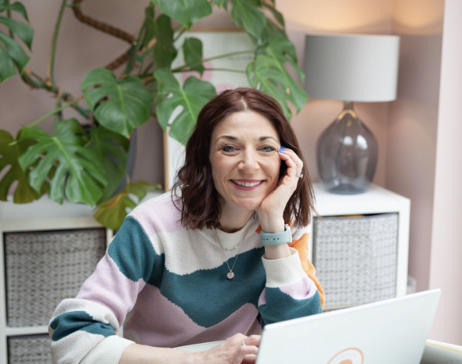kim sitting at her desk in a striped jumper
