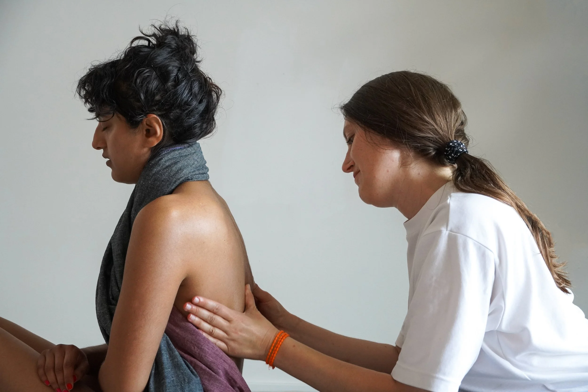 A healthcare professional examining a woman’s back and shoulder area during a medical consultation.