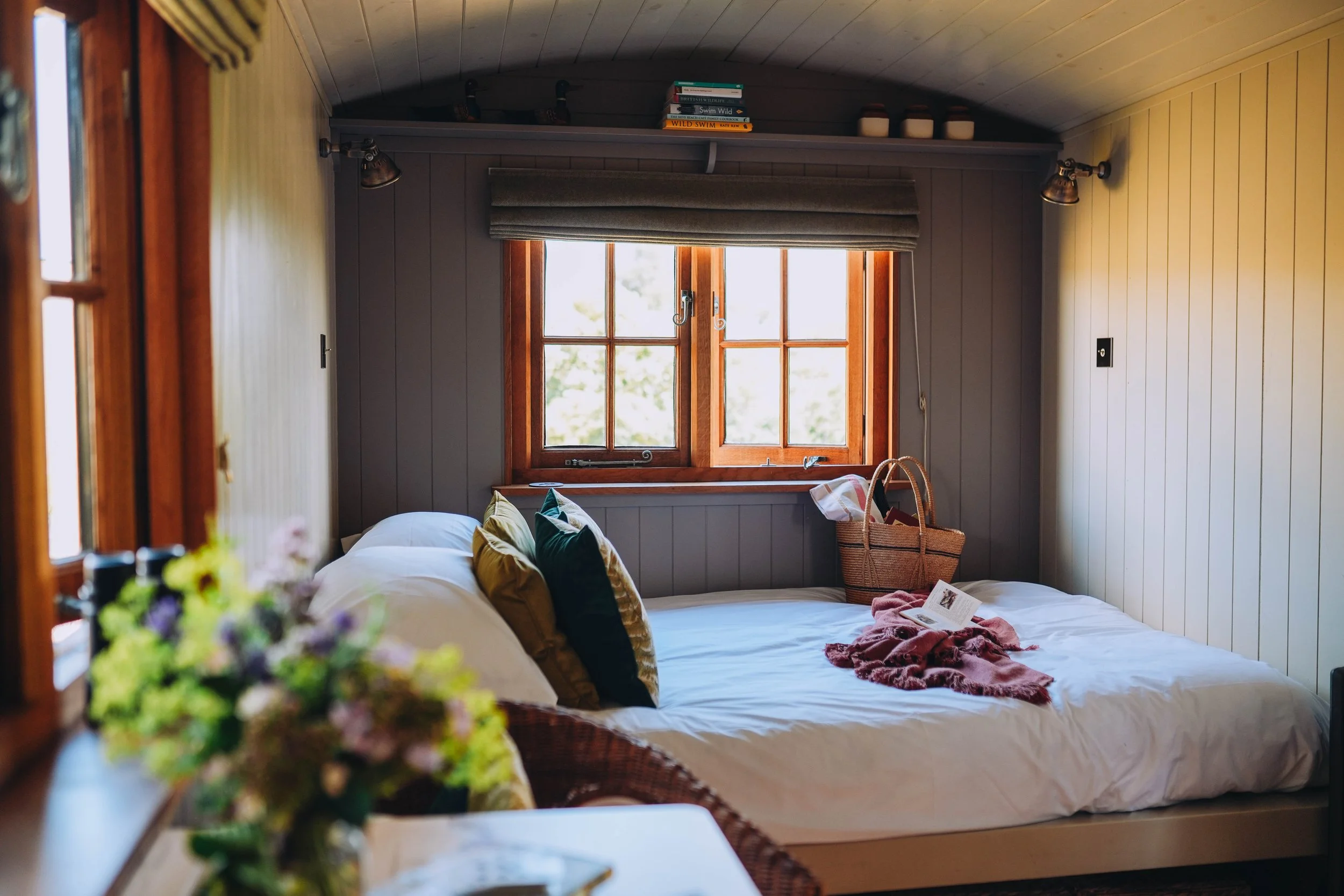 Inviting bedroom featuring cosy blankets and fresh flowers.