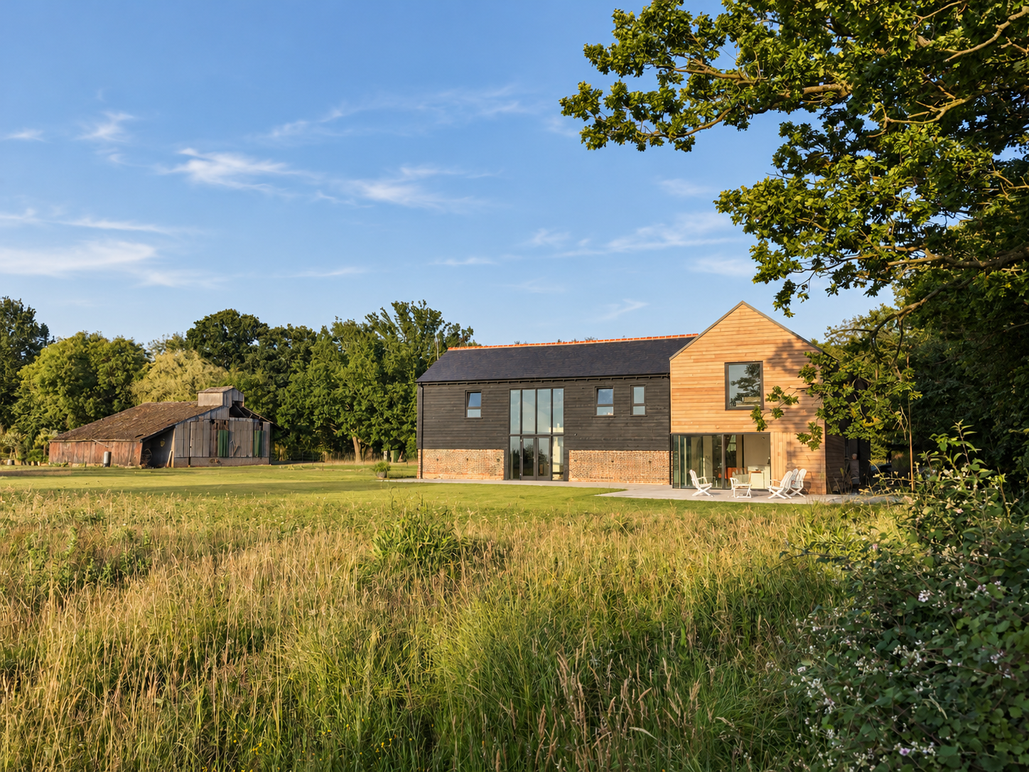 Little Nuntys from the meadow: black weatherboarded 1850s barn with a timber-clad new build extension