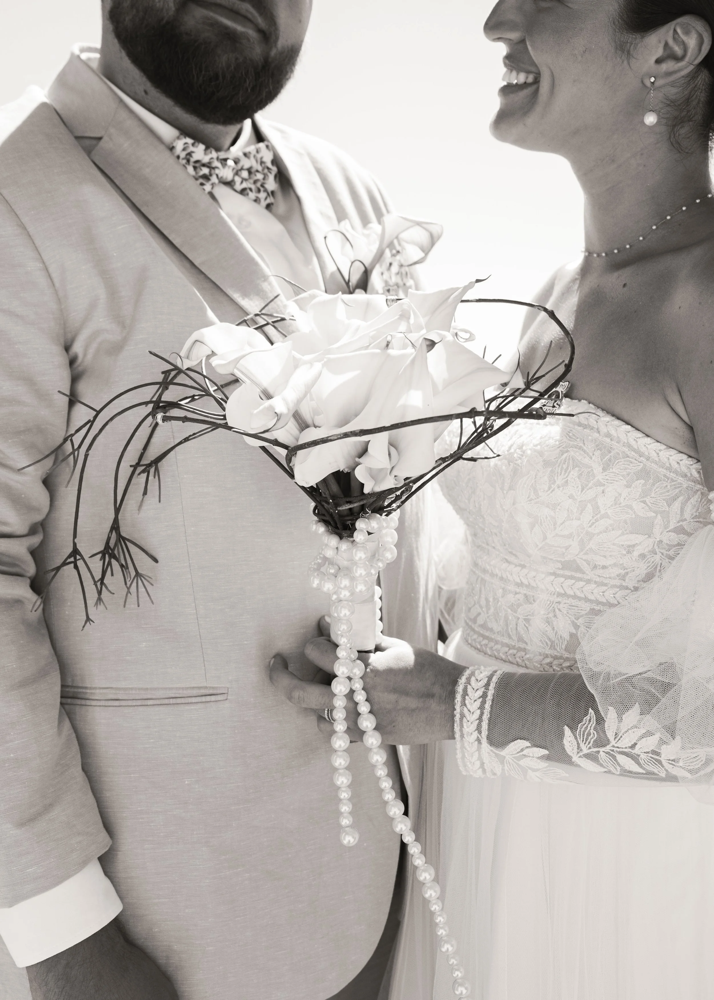 Un couple marié tenant un bouquet de fleurs lors de leur mariage, image en noir et blanc.