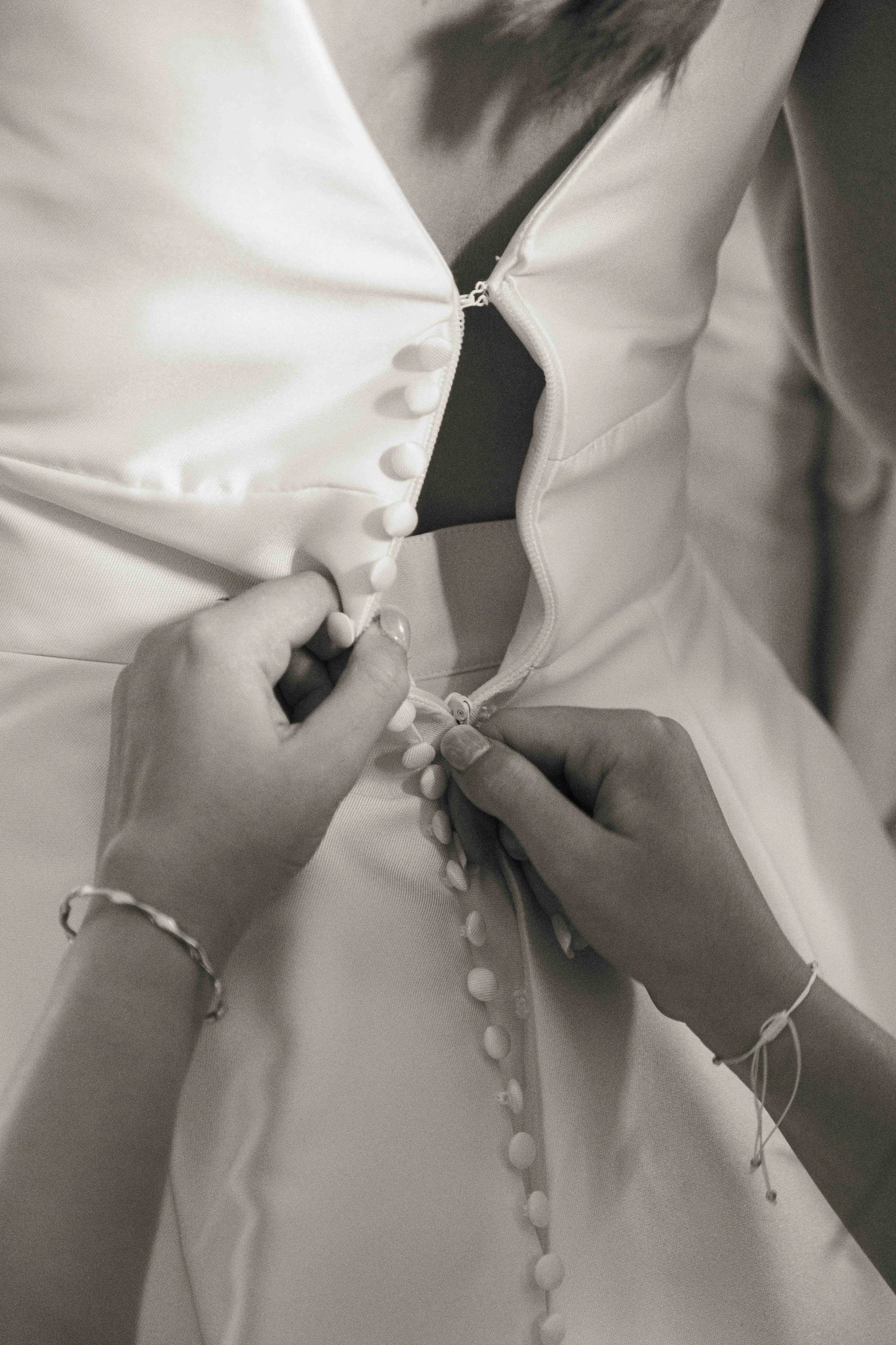 Une personne boutonant la fermeture d'une robe ou d'une veste blanche