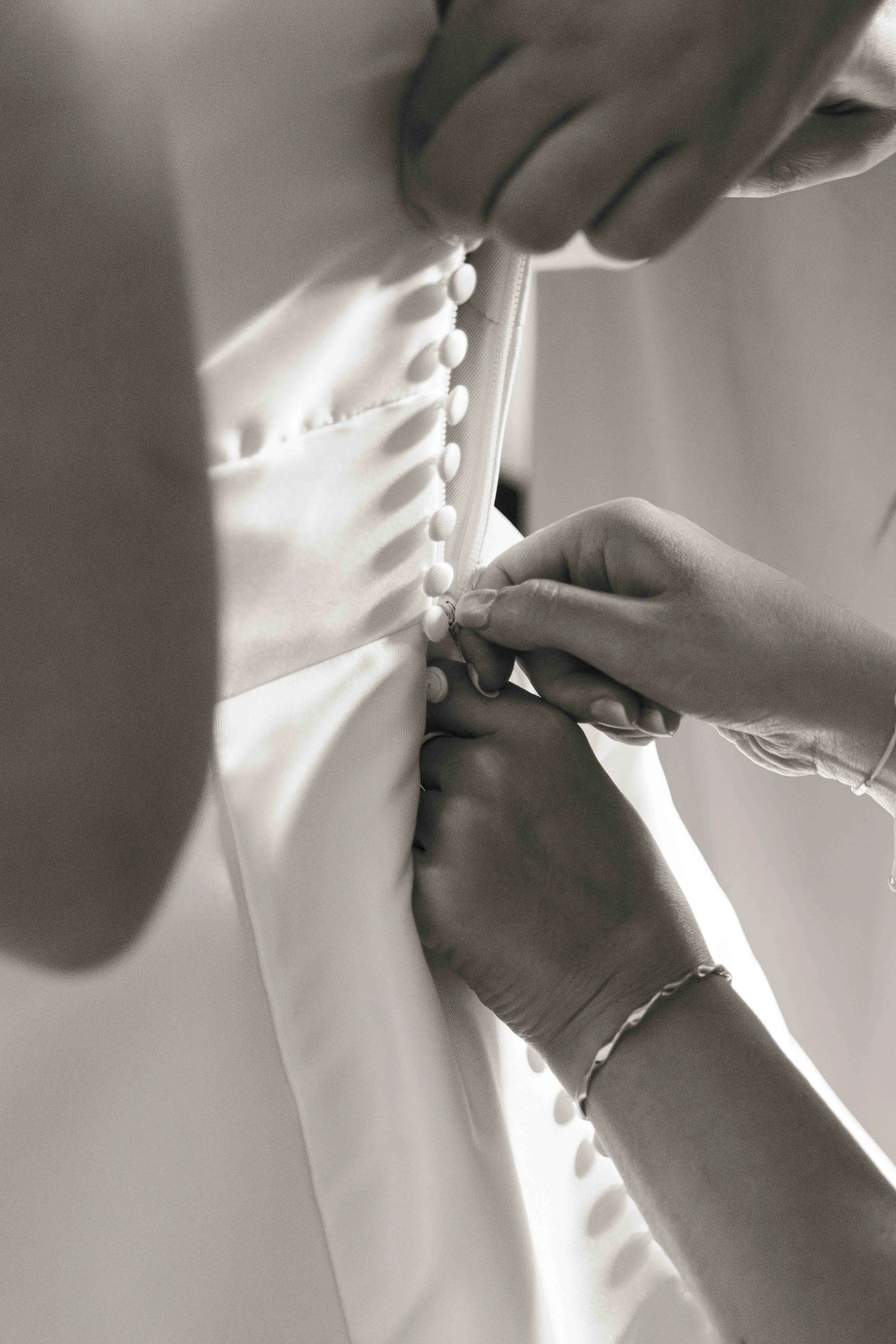 Femme en train de boutonner la fermeture d'une robe de mariée à Grasse