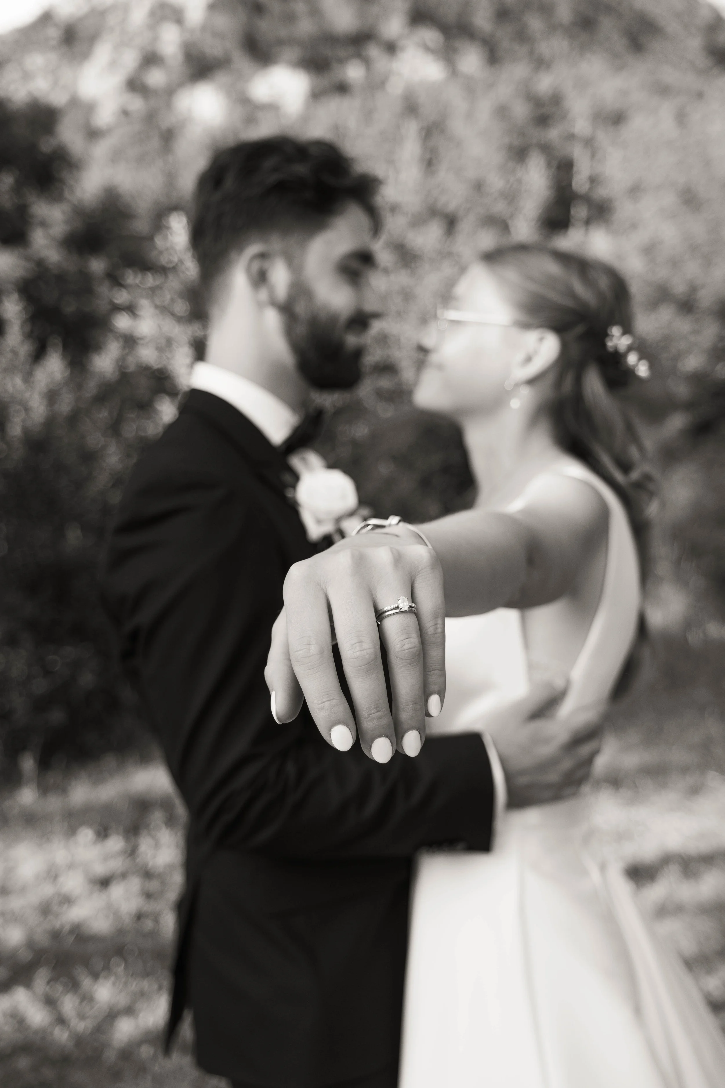 Une couple de mariés qui se tiennent l'un face à l'autre, la femme montrant leur alliance de mariage.