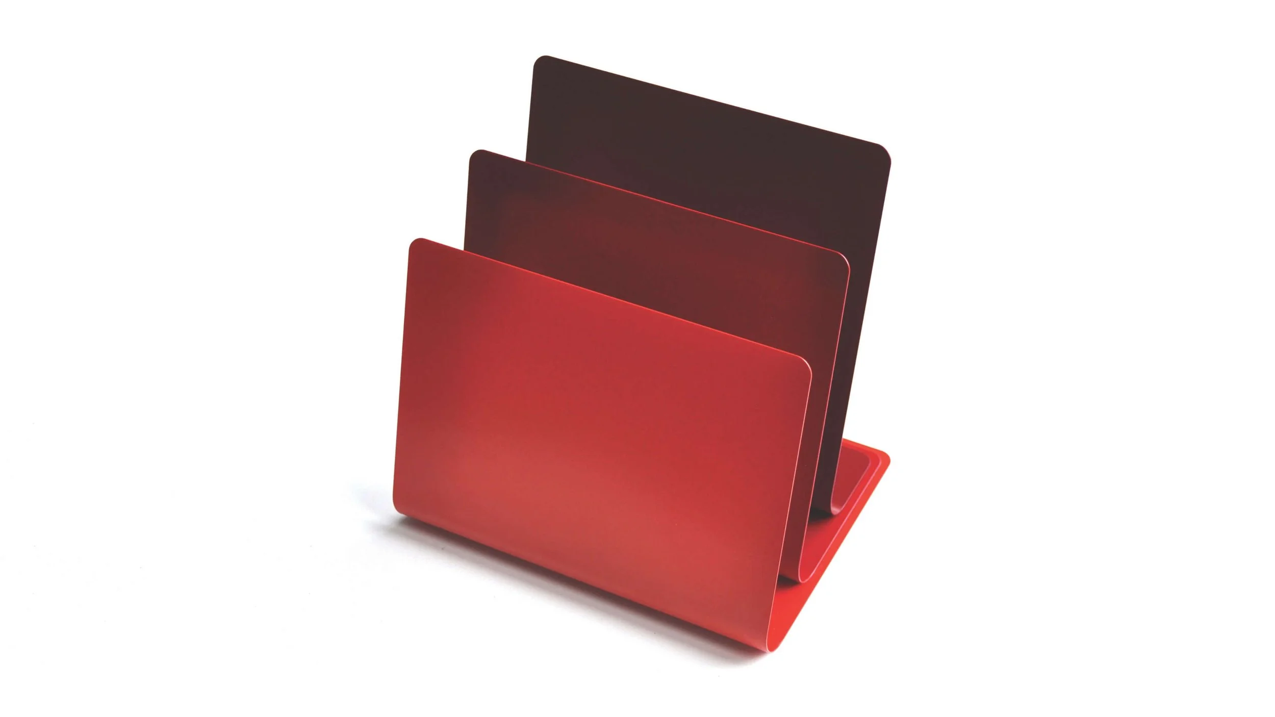The Strata magazine rack is made of 3 sheets of steel, each of a different shade of red, to reference sedimentary rock formations.