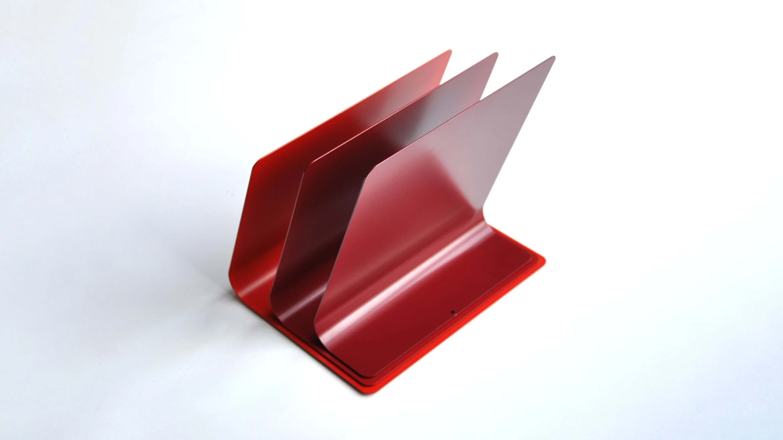 Rear view of a Strata magazine rack. The layers of steel, in their different shades of red, are clearly visible.
