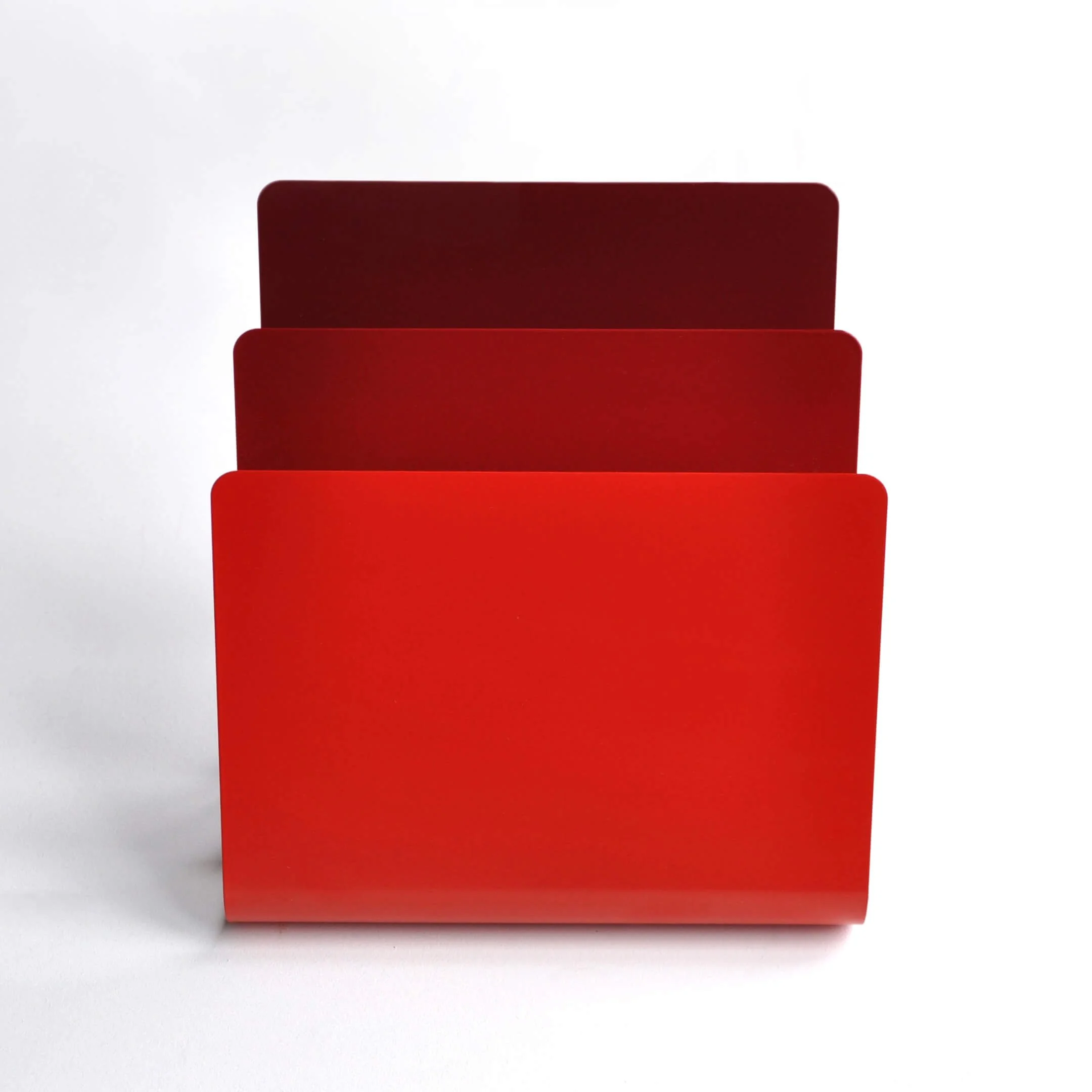 Front view of a Strata magazine rack. Different shades of red are applied to each layer to reference sedimentary rock formations.