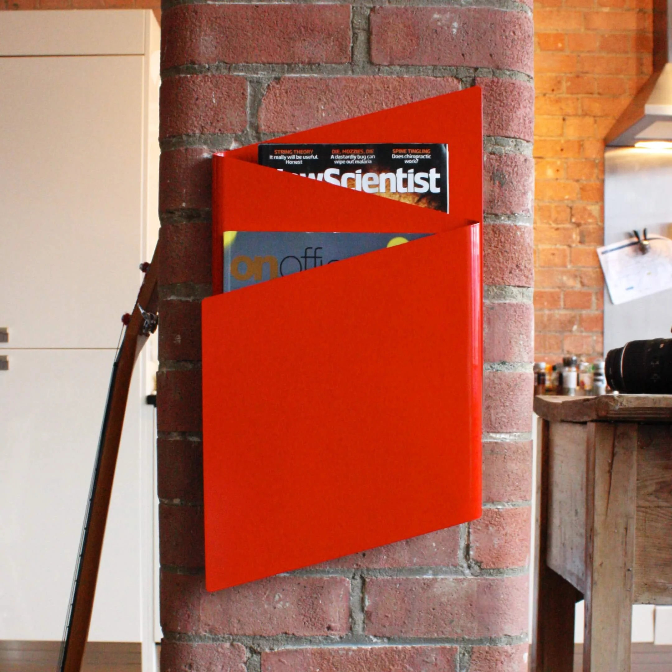 Front view of a red, wall-mounted Flow magazine rack.