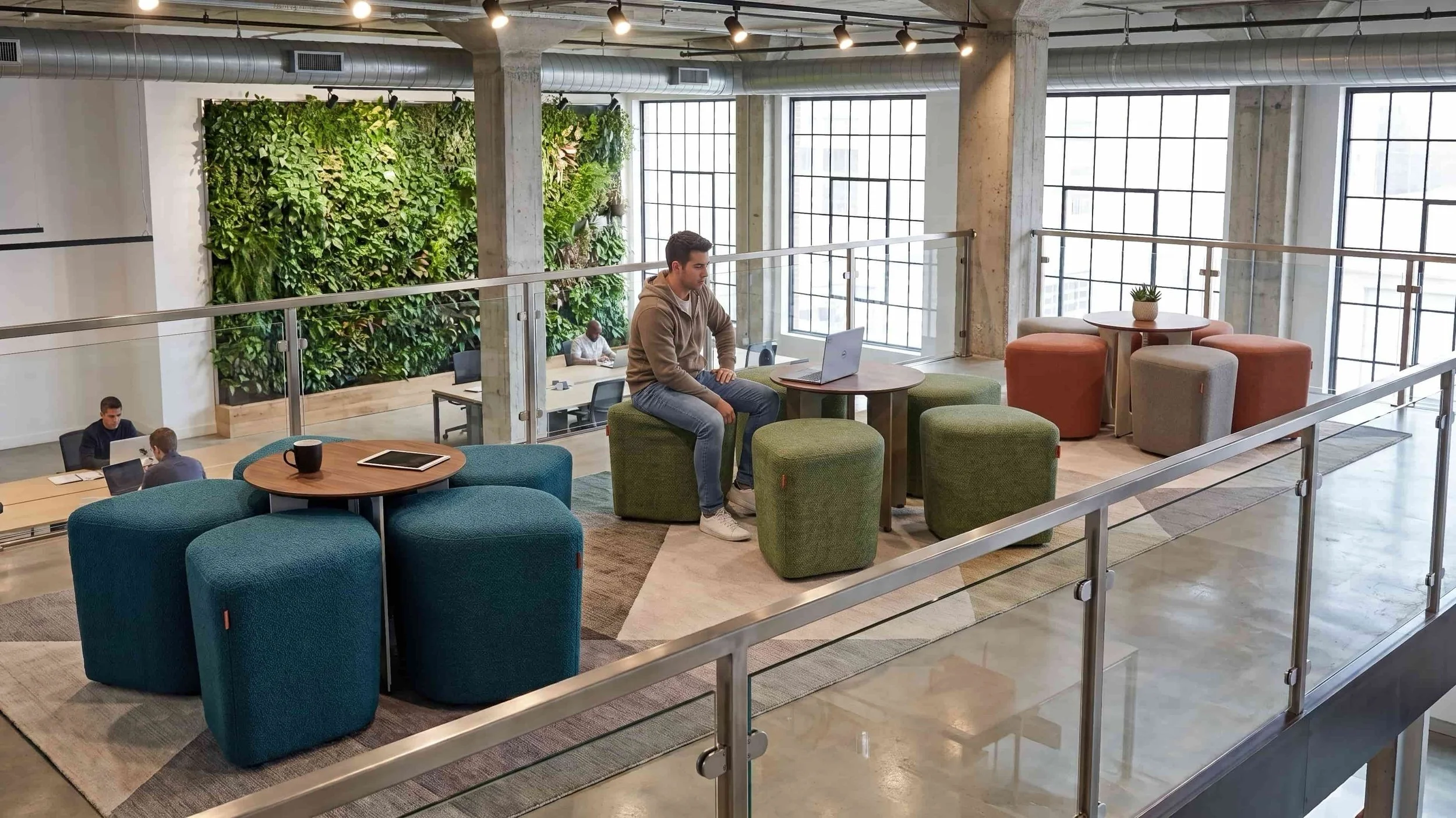Three Blossom Seating Systems with Tables in a breakout area of a busy office.