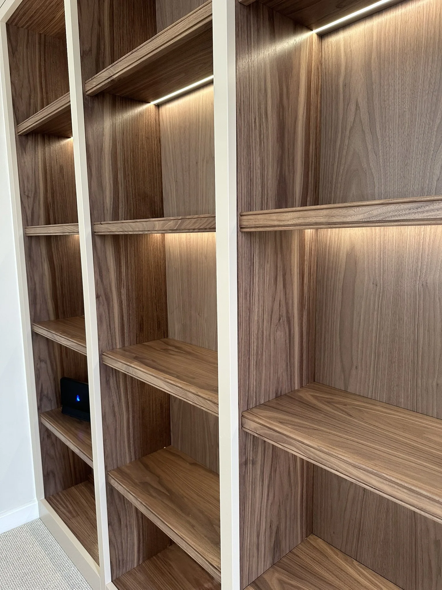 Empty wooden bookshelves with built-in lighting in a modern interior space.