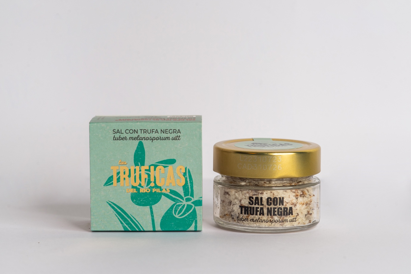 Box and jar of black truffle salt from Los Truficas del Rio Pilas, with the packaging on the left and the jar on the right, both placed on a plain white background.