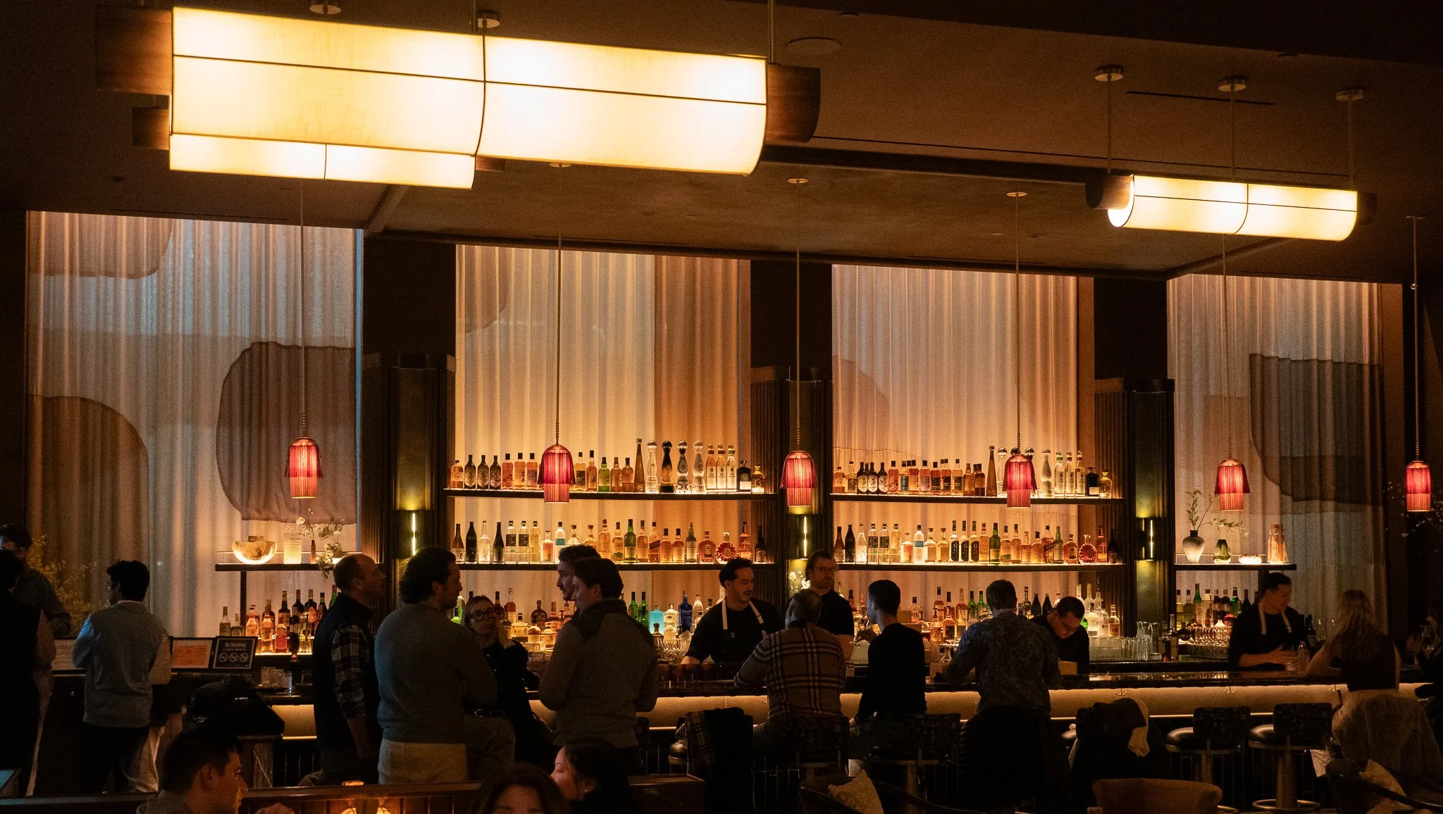 A busy manhattan restaurant with a back wall and decoupage upholstery in the windows
