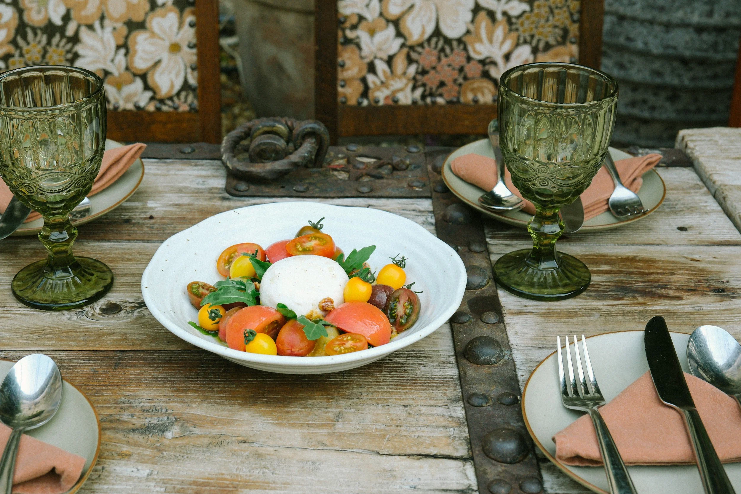 A tomato dish sititng on a rustic table setting.
