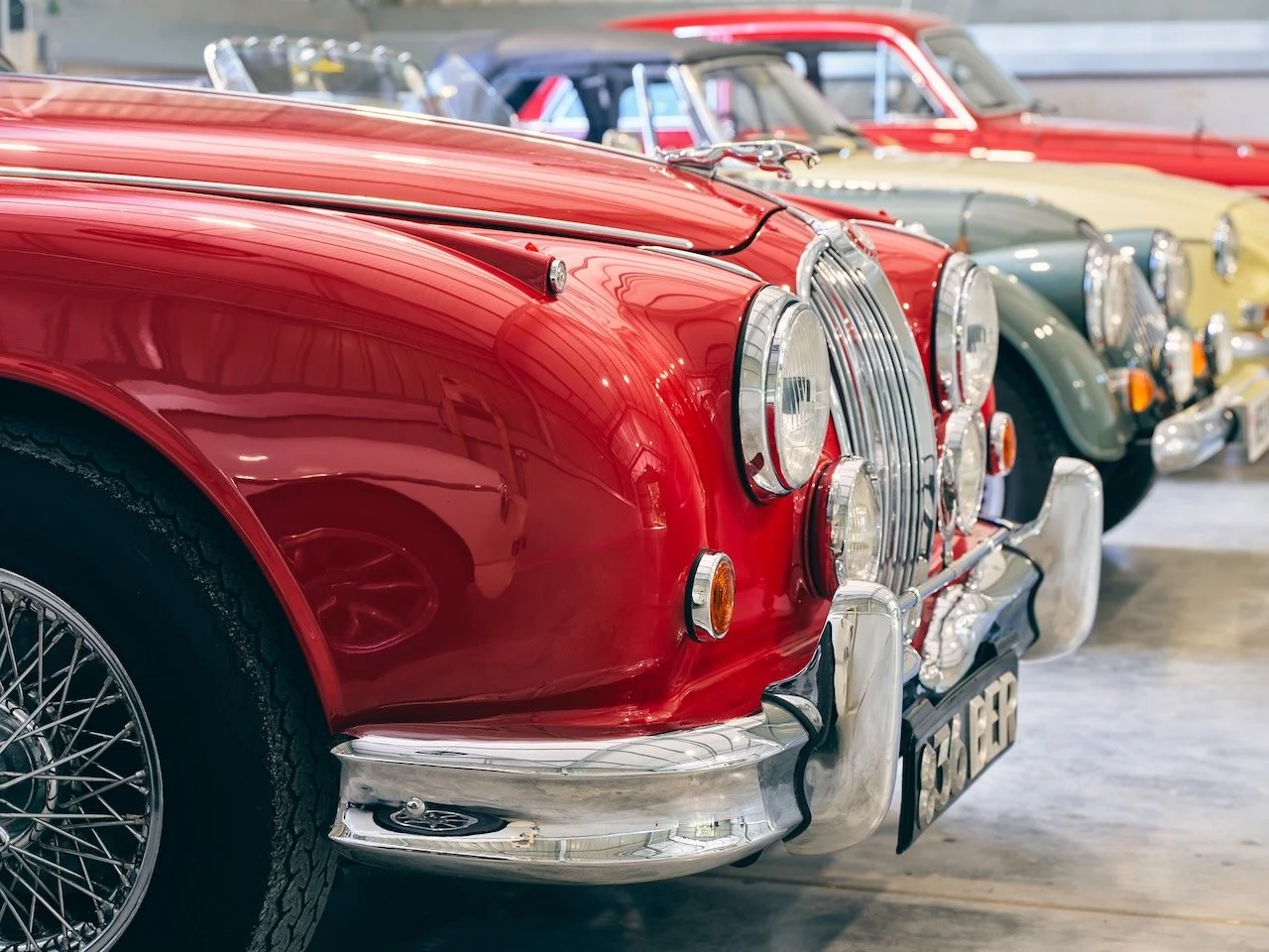 Close-up detail of classic cars stored at The Car Den, including a red Jaguar Mk2