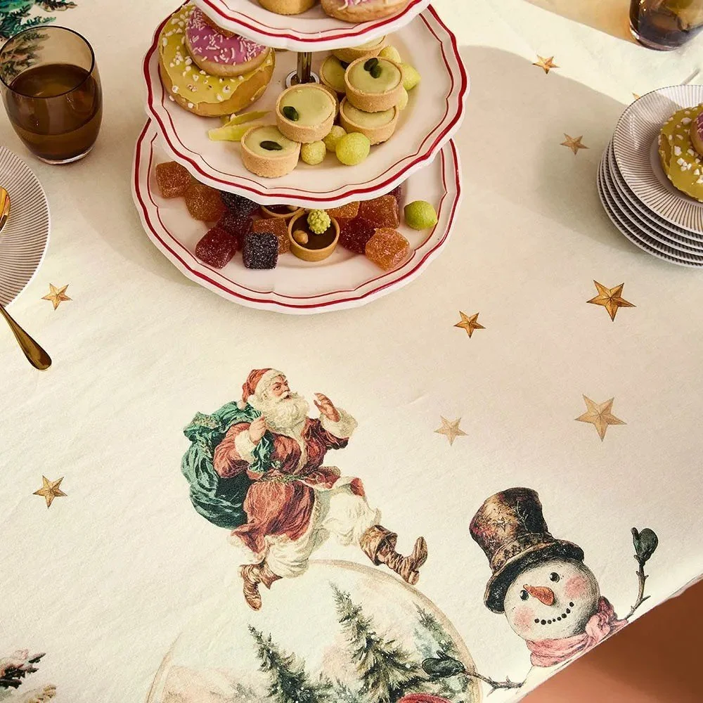 Vintage looking tablecloth showing stars, Santa, a snowman and a snow globe.