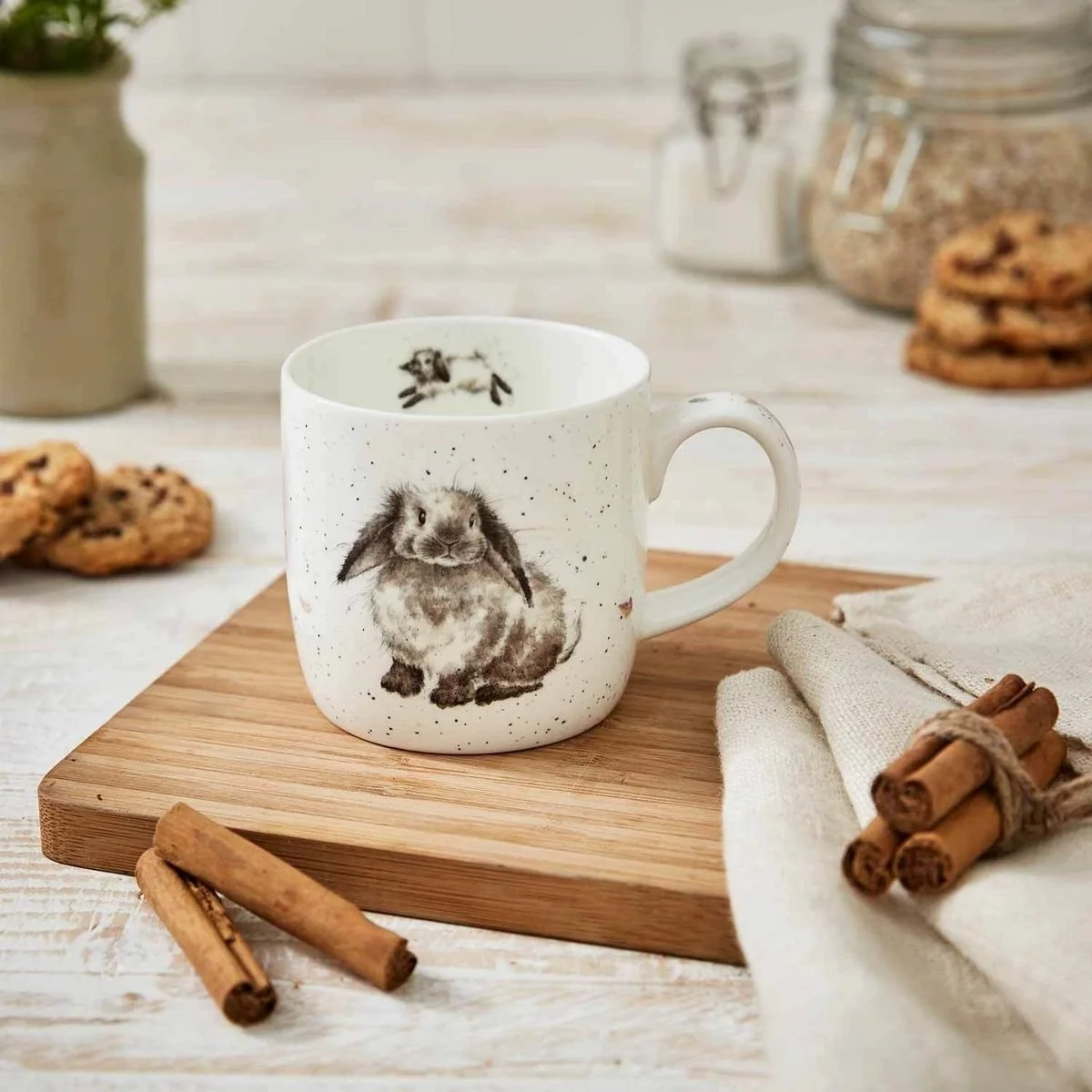 White mug with rabbit on decorated table sitting on wood cutting board tray.