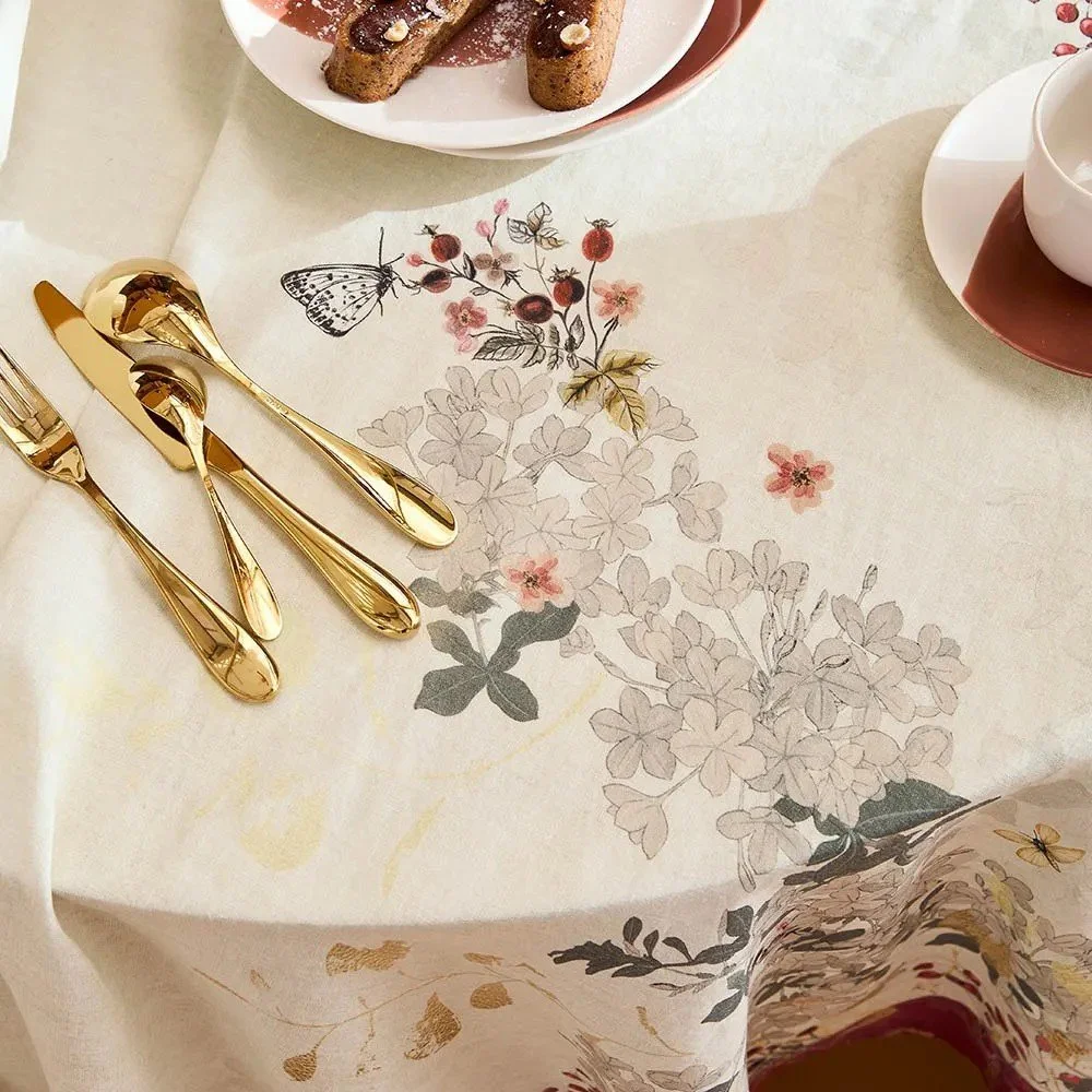 Vintage inspired tablecloth showing butterfly landing on flower and gold colored flatware.