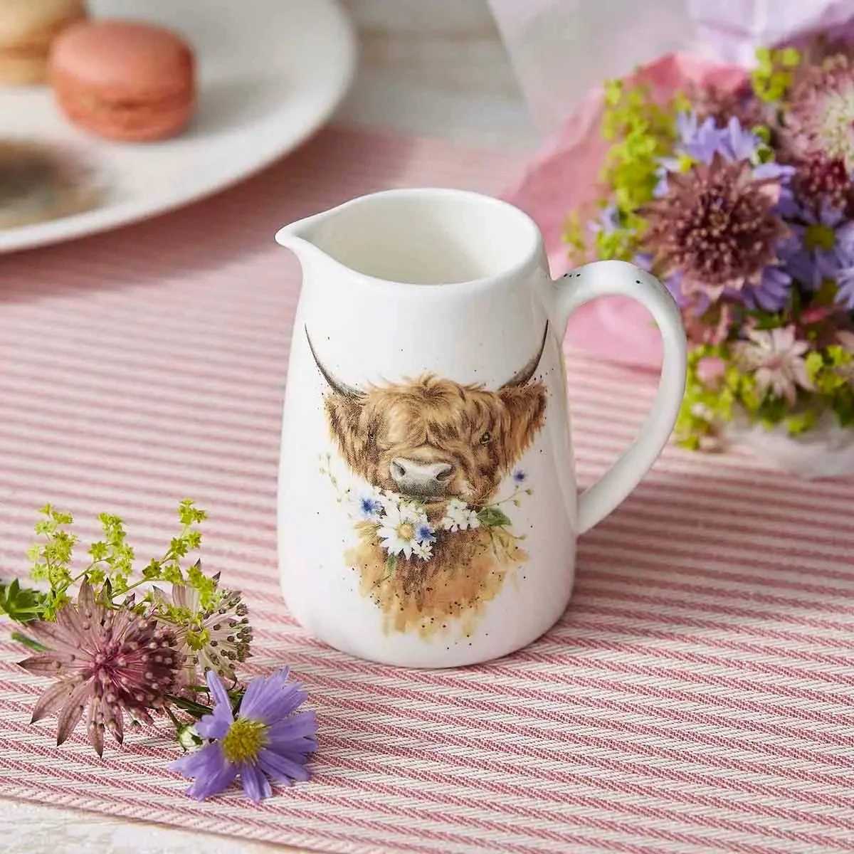 highland cow jug on tale with flowers.