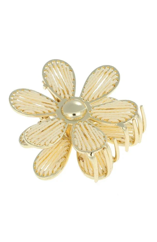 hair claw clip in the shape of a daisy with gold detail and yellow thread.