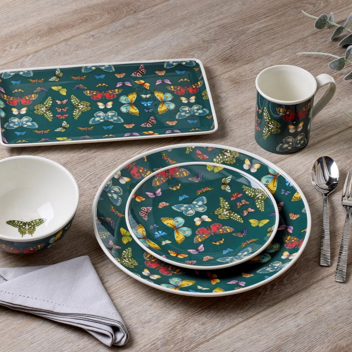 Dishware set of hunter green tableware each adorned with numerous butterflies.