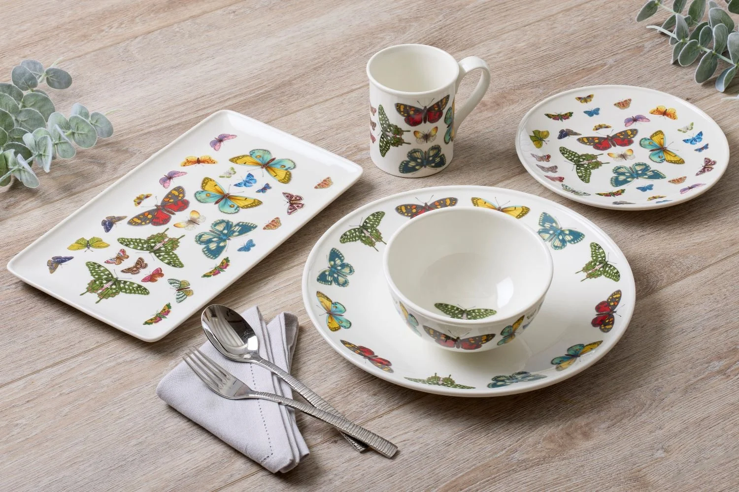 Entire butterfly place setting, each piece white with numerous butterflies.