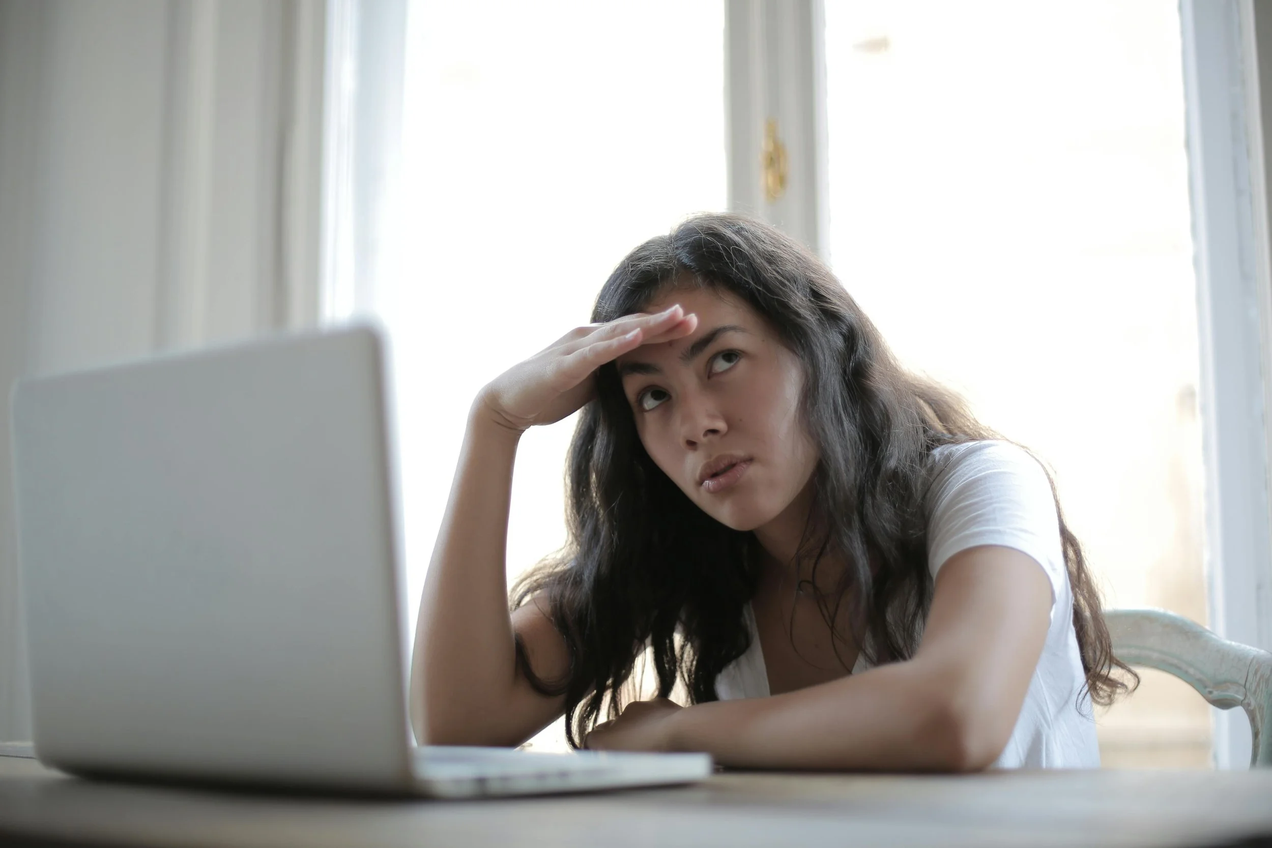 A woman sitting at her computer looking confused