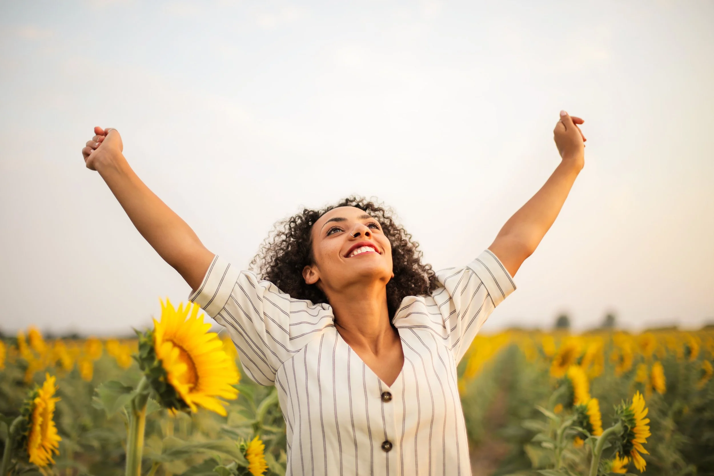Happy woman standing in a sunflower field.