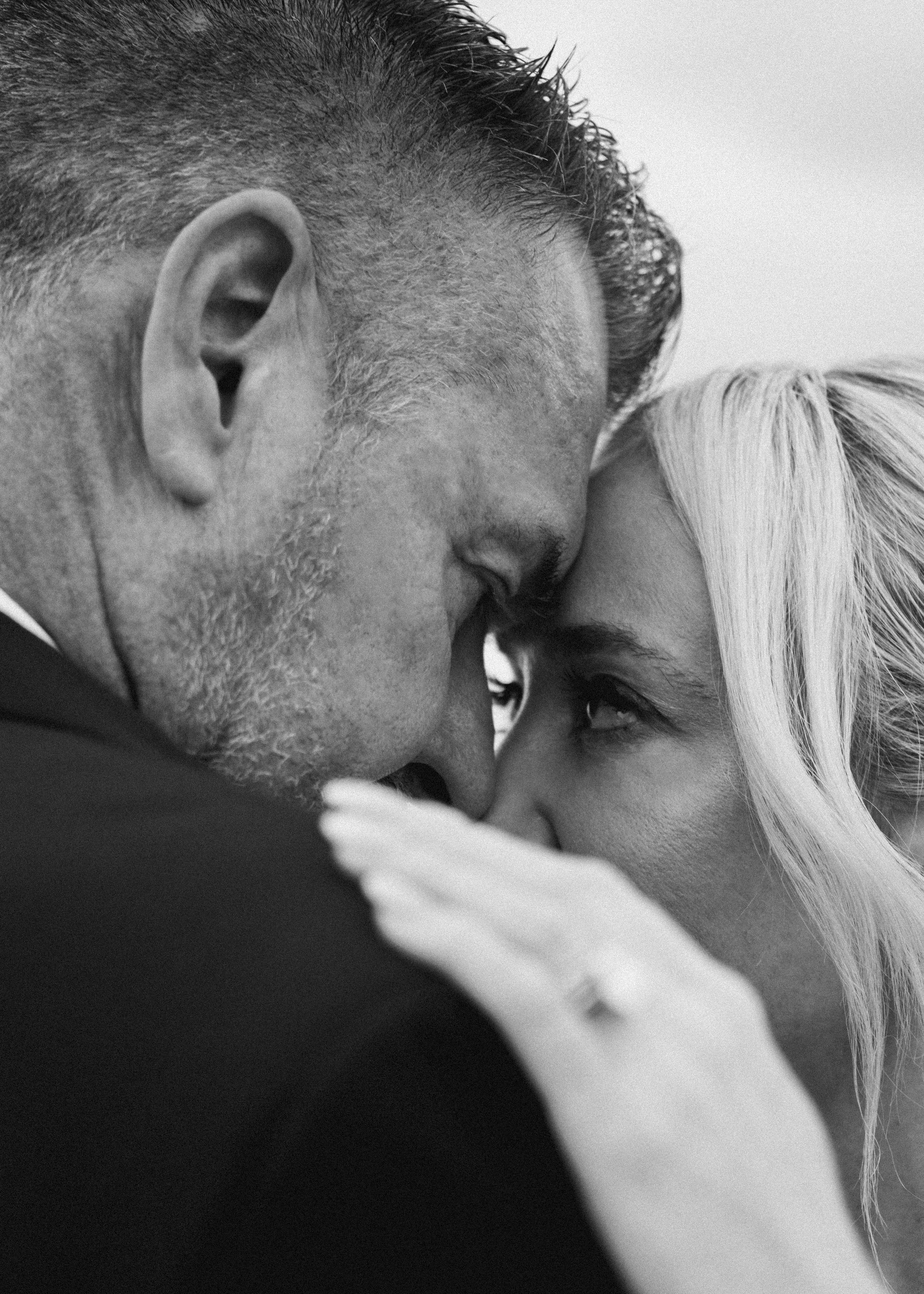 A close-up black and white photo of a man and woman face to face, nose to nose, with eyes locked, showing an intimate moment.