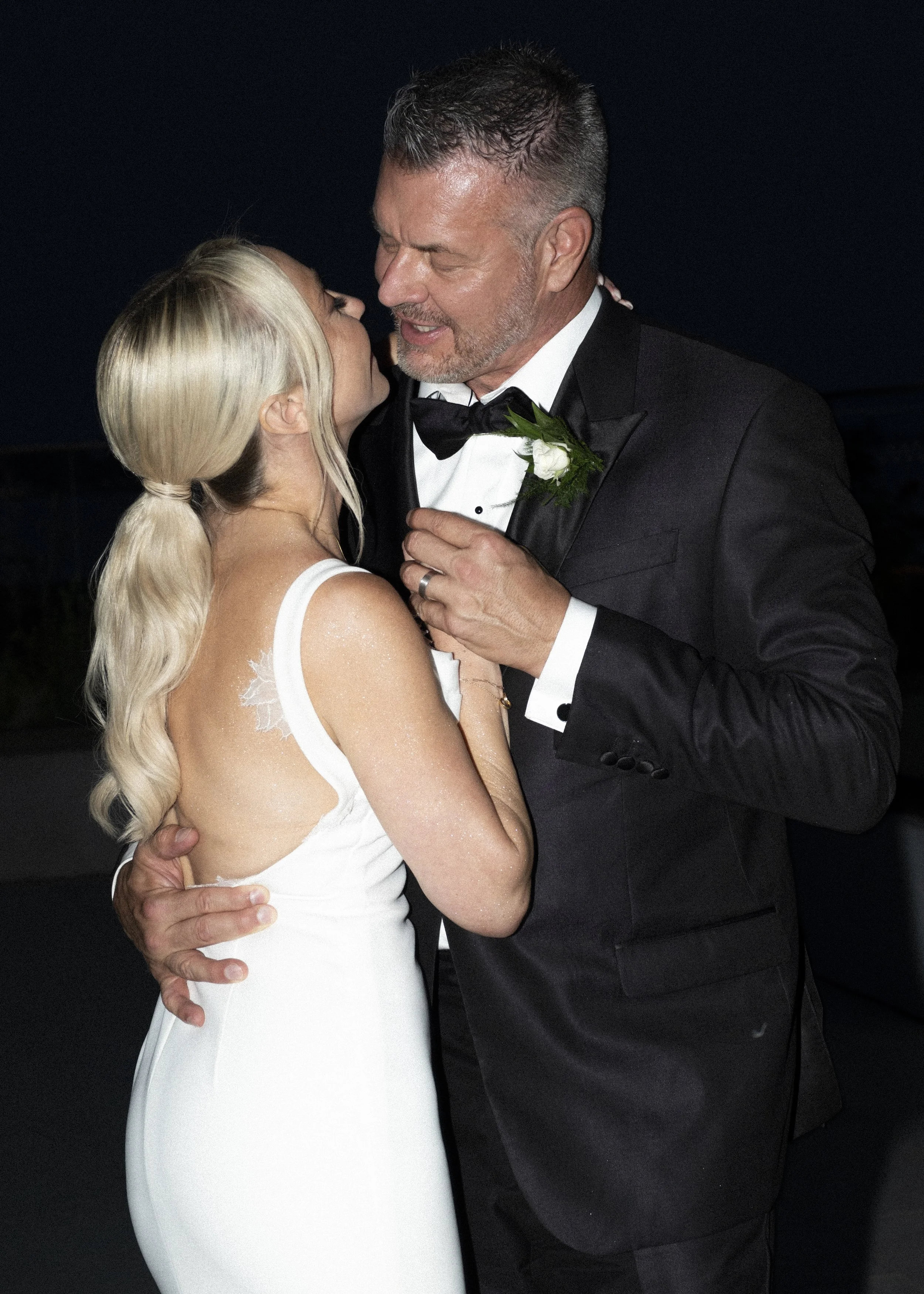 A couple dressed in wedding attire, sharing a dance and looking into each other's eyes.