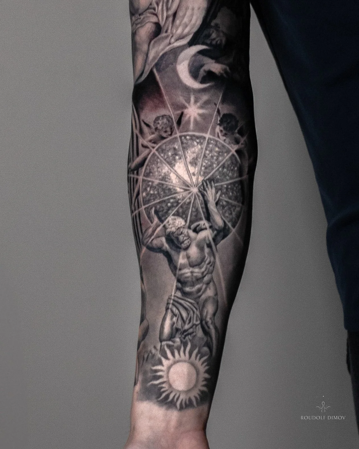 Black and grey realism tattoo of Atlas holding a celestial sphere on the inner forearm, with micro angels, the moon, and the sun, as part of a Renaissance-inspired sleeve.