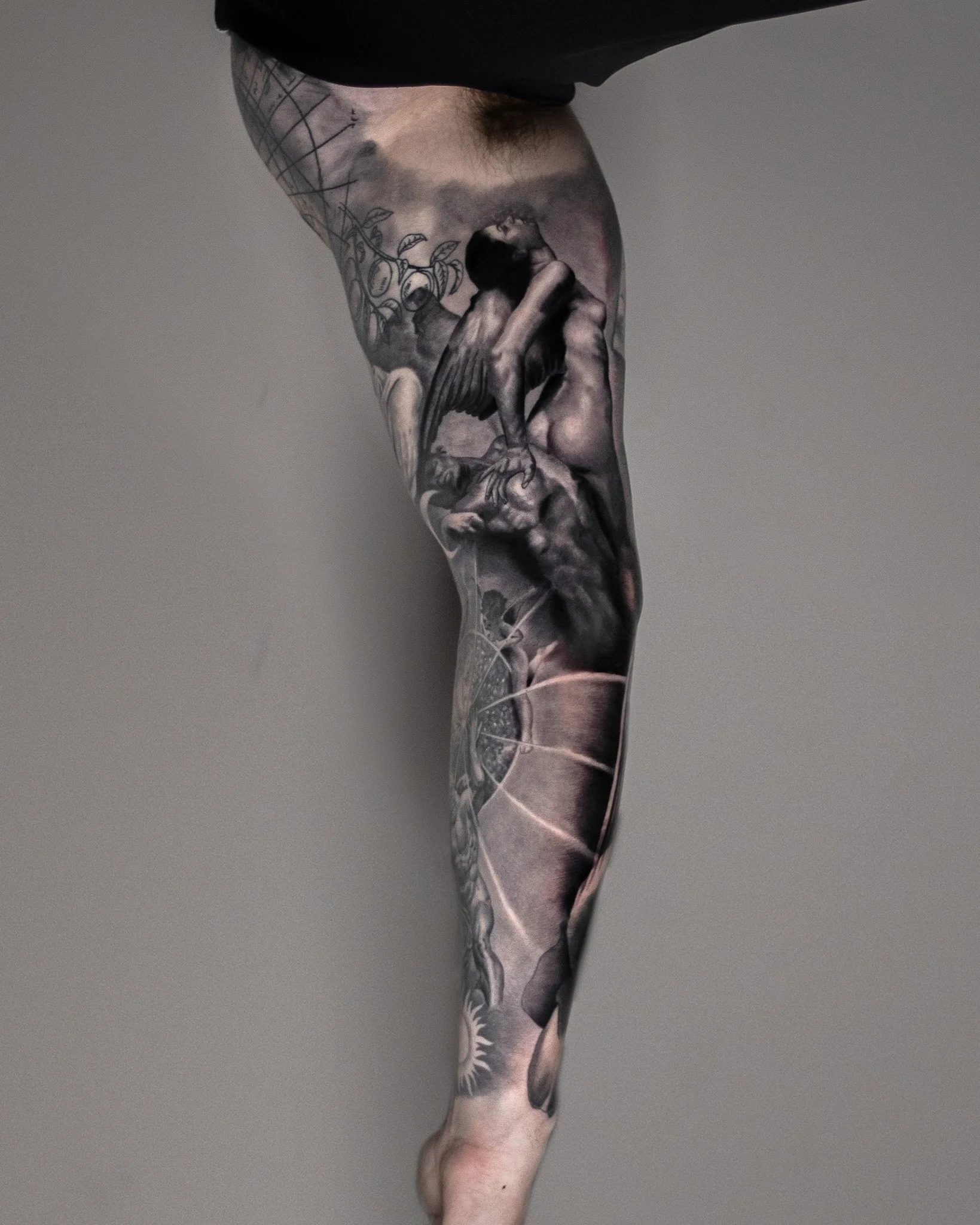 Black and grey realism sleeve showing a Roberto Ferri figure, celestial sphere, and sun on the inner arm with Renaissance sketchwork near the shoulder.