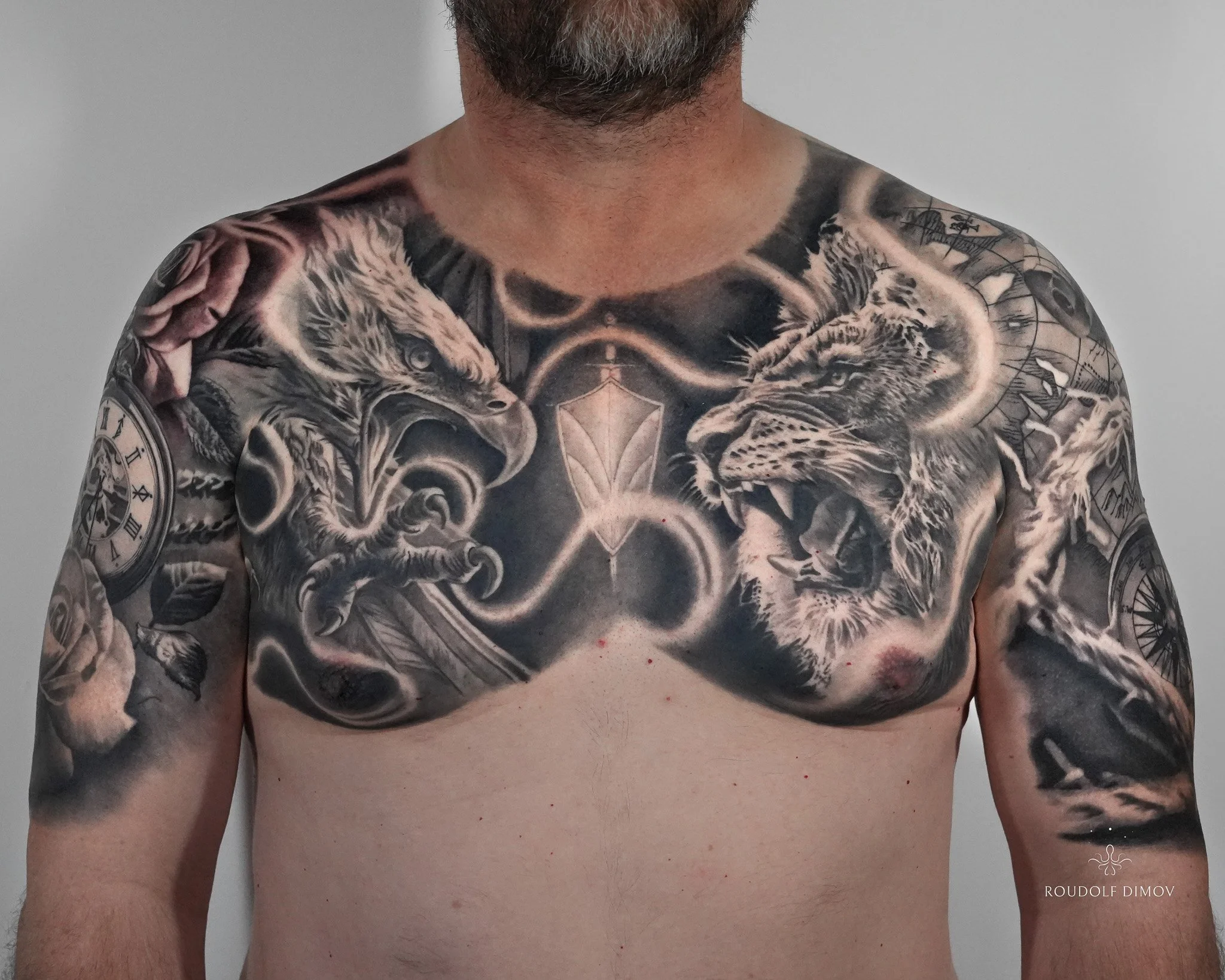 Black and grey realism chest tattoo featuring an eagle on one side, a lion on the other, and flowing negative-space lines connecting the design into both upper arms.