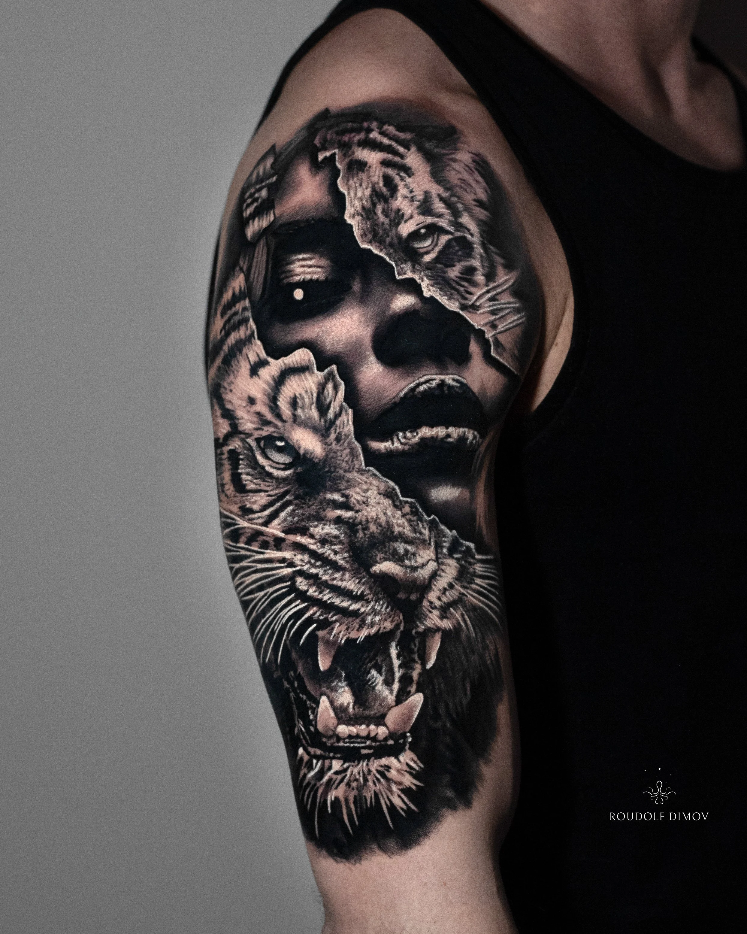 Tiger and woman portrait tattoo on the upper arm in black and grey realism, featuring detailed textures and contrast. Tattoo artist Roudolf Dimov, London.