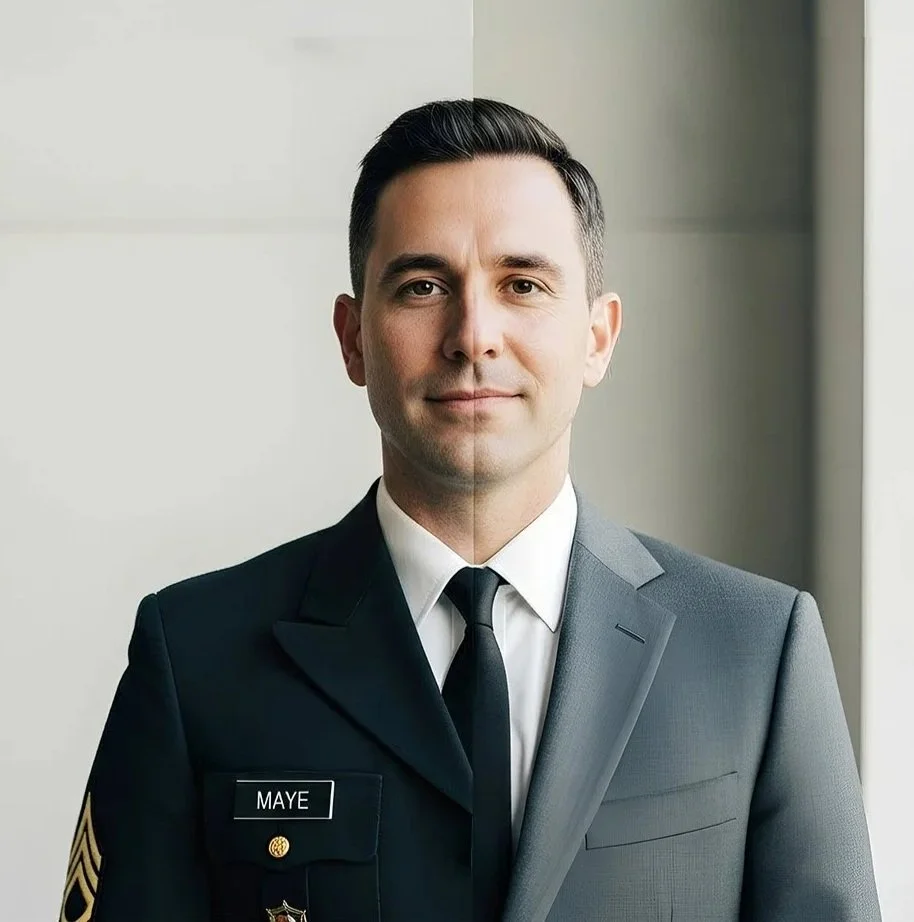 A man in a half military uniform, half business suit standing indoors near a window, smiling slightly. He has dark hair and is wearing a black tie and a dark grey suit with a name tag that reads 'MAYE'.
